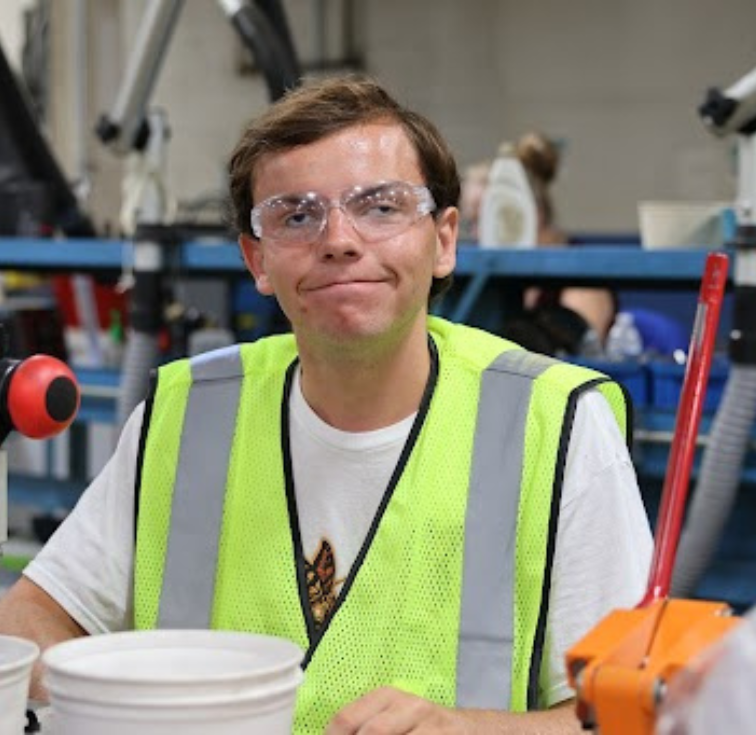 Student worker in safety vest inside industrial setting