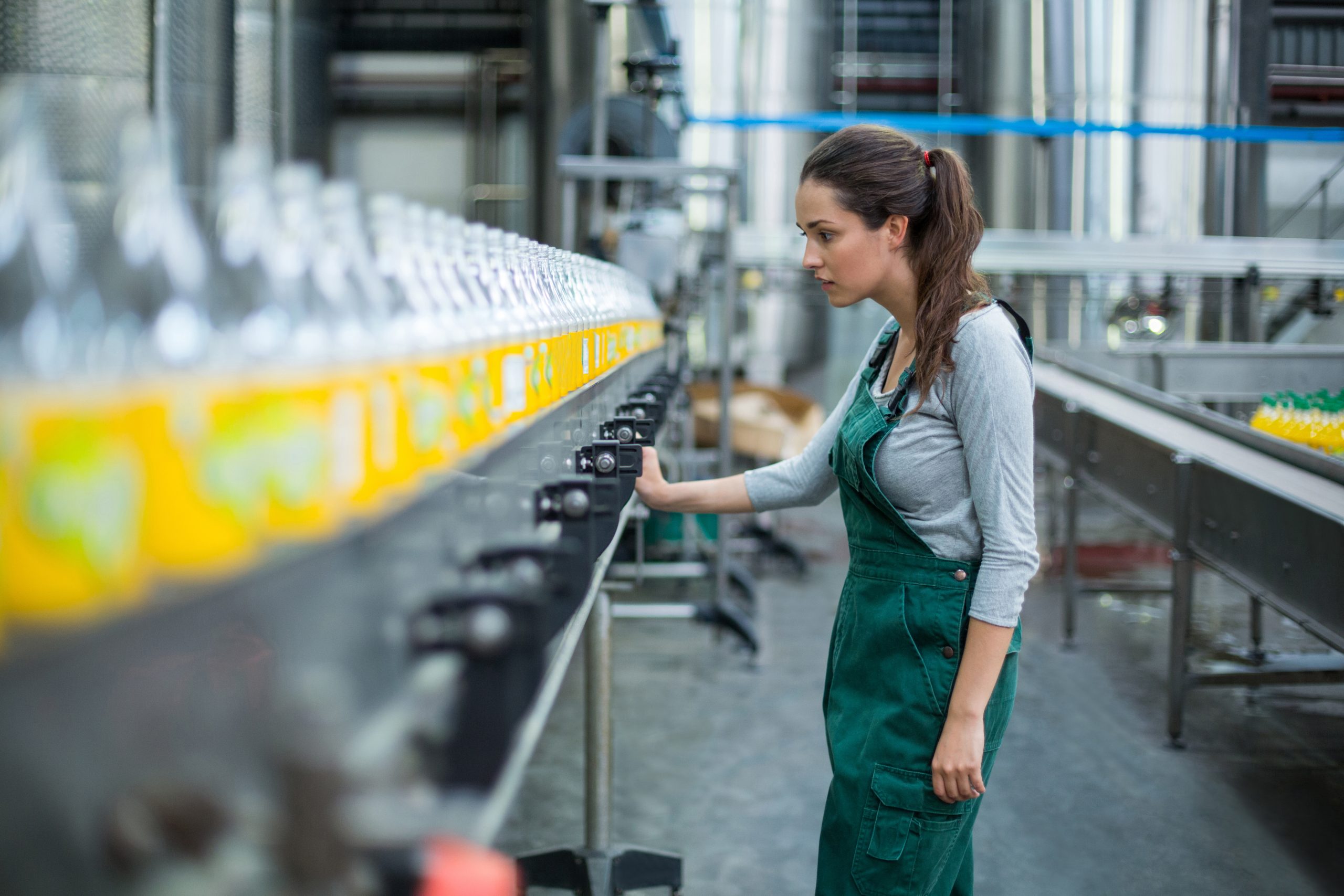 Factory worker inspecting bottles on production line